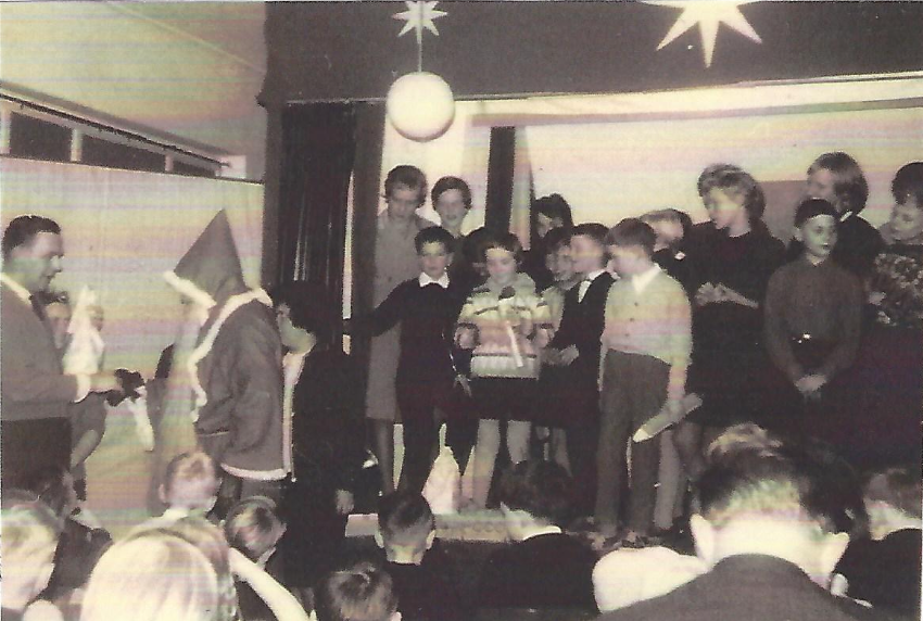 Das Foto zeigt, wie sich Kinder in der Schule Mehrum um eine als Weihnachtsmann verkleidete Person stehen.